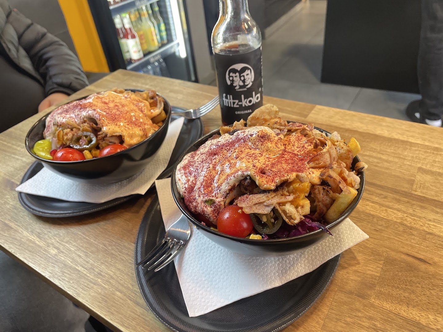 Zwei Teller mit Fleisch und Salat, dahinter eine Flasche Fritz-Kola